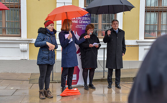 Vier Menschen stehen unter einem Regenschirm