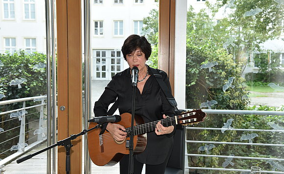 Bente Kahan singt ein Lied und begleitet sich mit der Gitarre