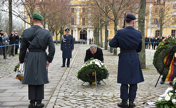 Landtagspräsident legt einen Kranz an einer Gedenkstele nieder.