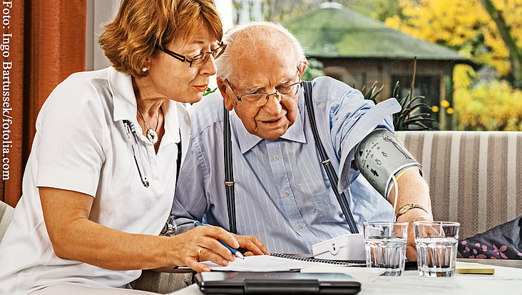 Eine Ärztin widmet sich einem hilfebedürftigen Senior.