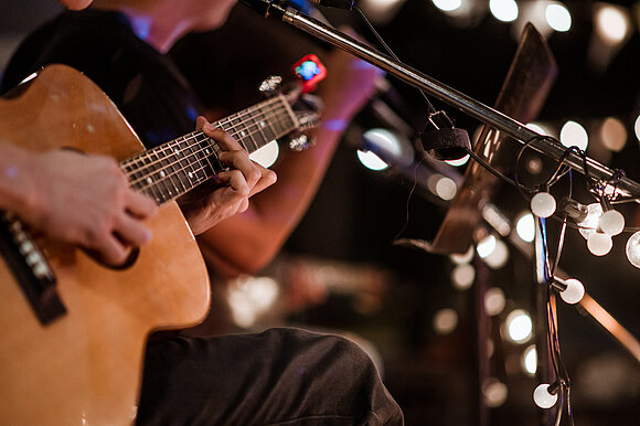 stock.adobe.com – Take Production Jemand hält eine Gitarre bei einem Konzert.