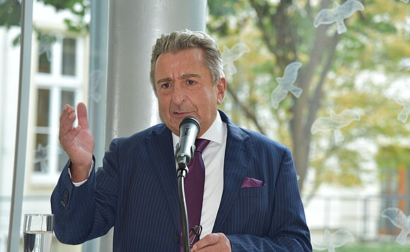 Landtagspräsident steht hinterm Mikrofon und spricht