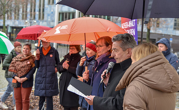 Landtagspräsident spricht vor Menschen in Mikrofon
