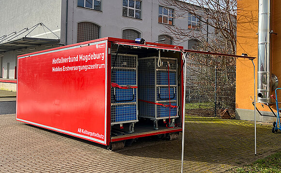 Roter Container, eine Seite ist wie ein Garagentor aufegklappt.