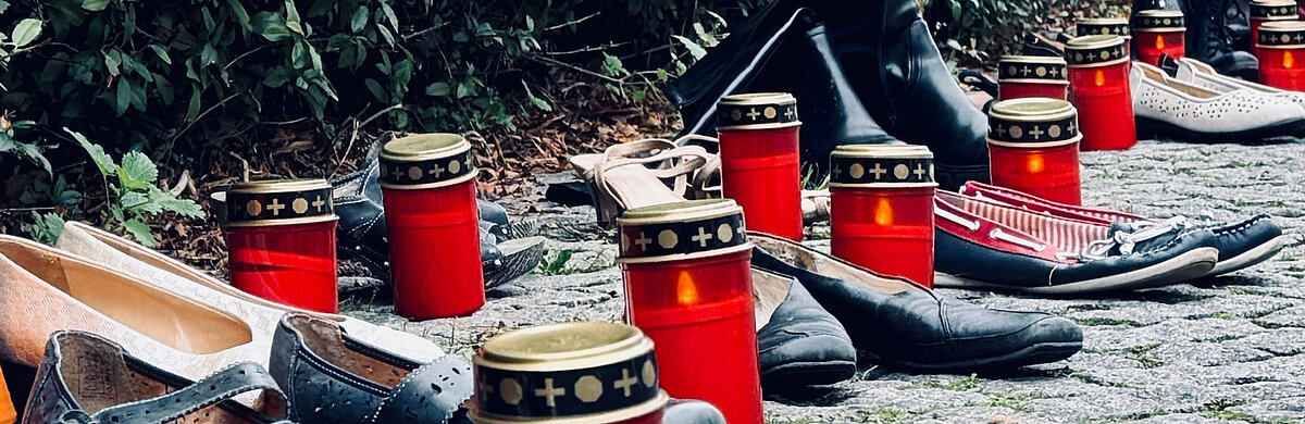 Mahnung: Für jeden 2025 in Deutschland verübten Femizid ein Paar Schuhe und eine Grabkerze.