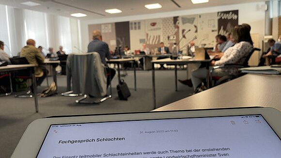 Blick über iPad-Mitschriften hinweg in den Sitzungsraum des Ausschusses.