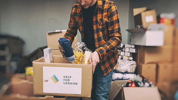 SkyLine - stock.adobe.com Ein Mann packt einen Karton mit Hilfsgütern. Die aus der Ukraine Geflüchteten werden auch in Deutschland aus der Zivilgesellschaft heraus mit Nahrungsmitteln und anderen Dingen des Alltags versorgt.