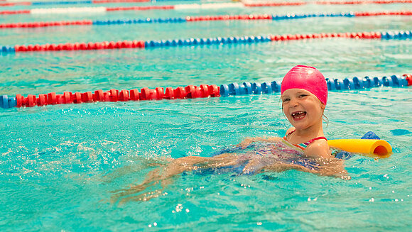 Kleines Mädchen lernt schwimmen in Schwimmbecken.