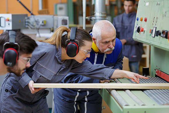 Zwei Azubis lassen sich vom Meister die Arbeit erklären. Das Handwerk ringt um beruflichen Nachwuchs.