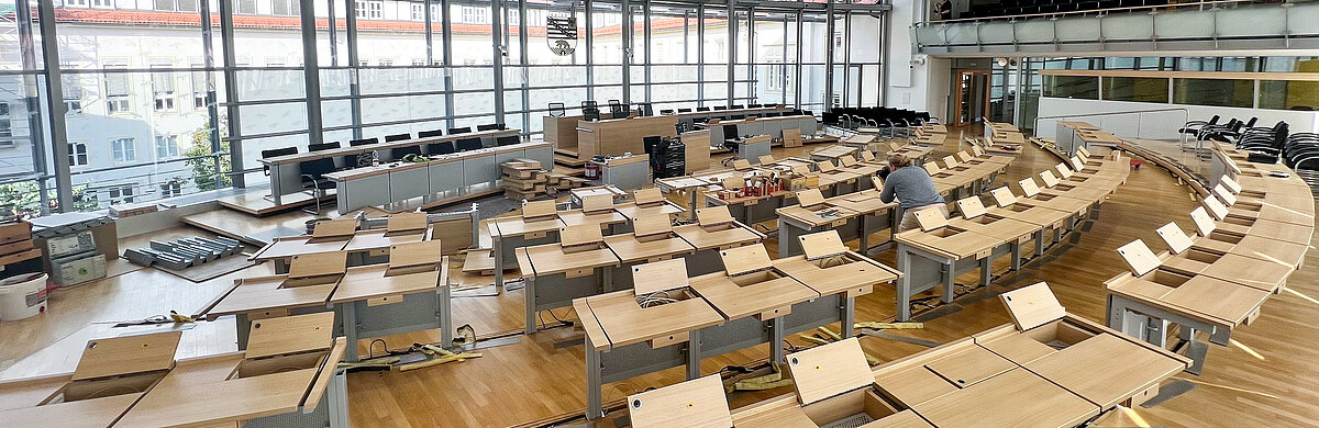 Blick in den leeren Plenarsaal, in dem noch Tische zusammengebaut werden.