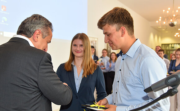 Präsident gratuliert zwei jungen Menschen.