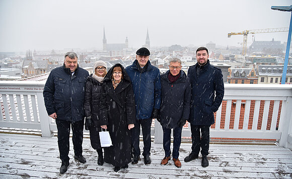 Litauische Delegation vor der Skyline von Halle im Schneefall.