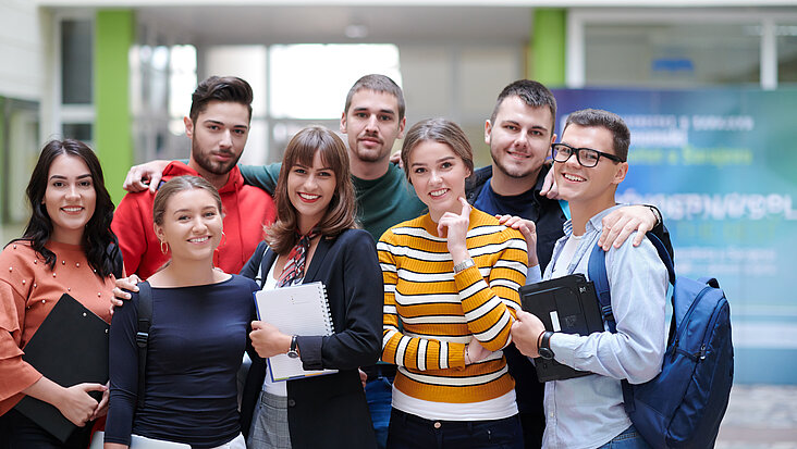 Gruppen von Studenten steht im Flur der Uni
