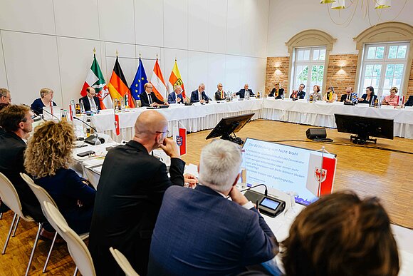 Landtag NRW Männer und Frauen sitzen an einem großen Tisch und debattieren.