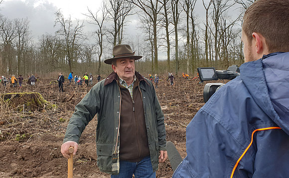 Landtagspräsident Schellenberger steht im Wald vor einer Kamera und gibt ein Interview.