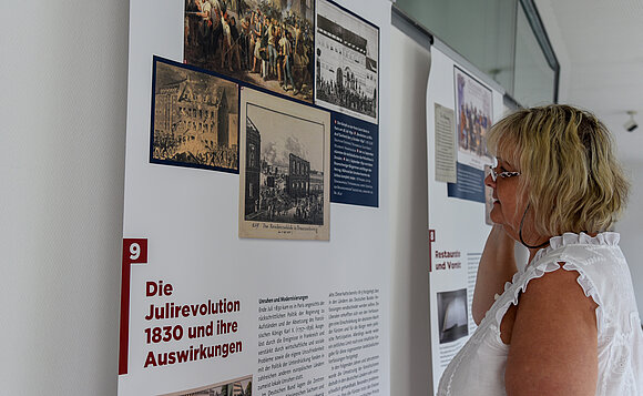 Eine Frau liest sich eine Tafel der Ausstellung durch.