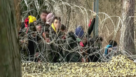 Flüchtlinge im Wald hinter Stacheldraht