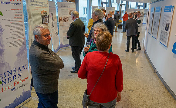 Mehrere Besucherinnen und Besucher stehen inmitten von Ausstellungstafeln.