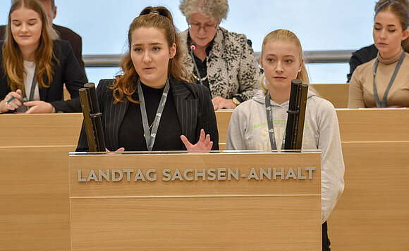 Zwei Jugendliche stehen am Rednerpult und bringen den Antrag einer der Fraktionen ins Jugendparlament ein.