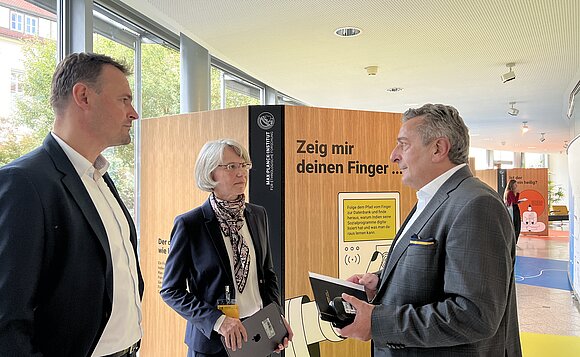 Menschen unterhalten sich vor Ausstellungstafeln.