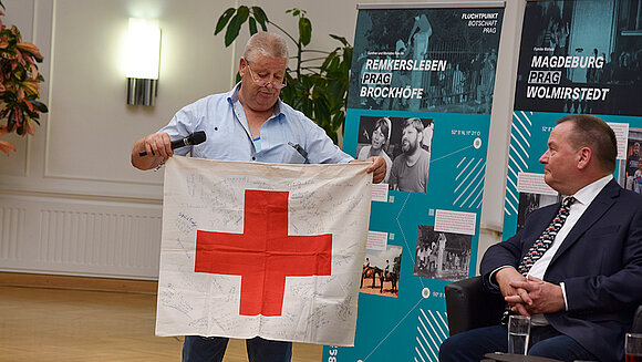 ltlsa/stb Zeitzeuge hält Fahne vom DRK mit Unterschriften in die Kamera