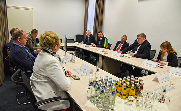 Abgeordnete sitzen um einen Tisch und unterhalten sich.