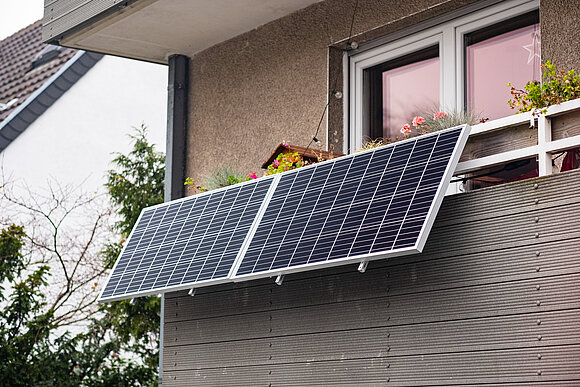 An einem Balkon ist eine kleine Solaranlage angebracht