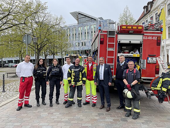Landtagspräsident steht mit Einsatzkräften vor Feuerwehrauto