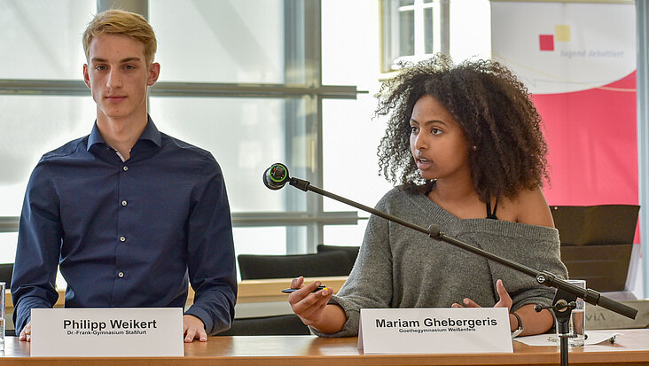 Zwei Teilnehmende von Jugend debattiert im Plenarsaal im Jahr 2021.