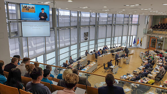 Blick von der Besuchertribüne in den Plenarsaal und auf die neuen Großbildschirme an der Seitenwand.