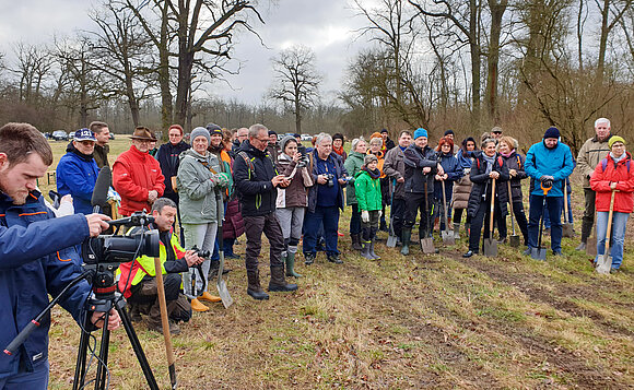 Abgeordnete und Bürger stehen im Halbkreis auf einer Lichtung im Wald.