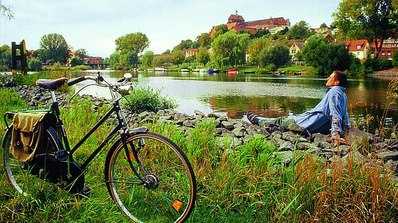 Radfahrer entspannt im Grünen an einem Fluss