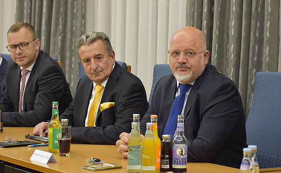 Landtagspräsident und zwei Abgeordnete sitzen am Tisch