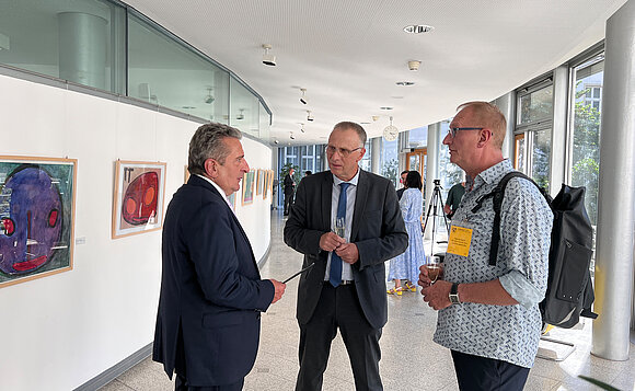 Menschen unterhalten sich vor Bildern der Ausstellung