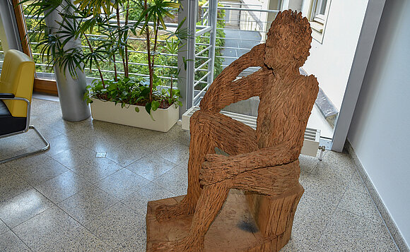 Eine der von Matthias Trott geschaffenen Holzskulpturen (sitzender Mensch), die in der Ausstellung zu sehen sind.