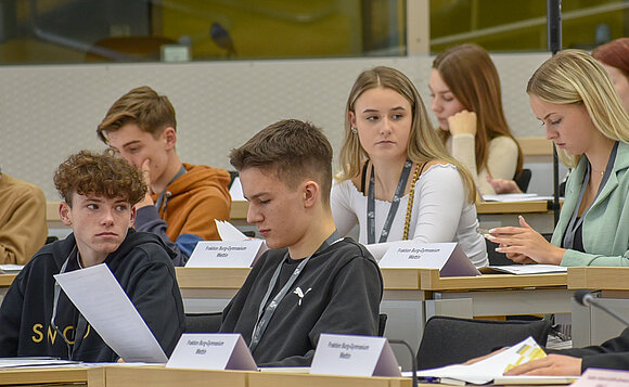 Jugendliche beim Jugendparlament im Plenarsaal beim Checken der Drucksachen.