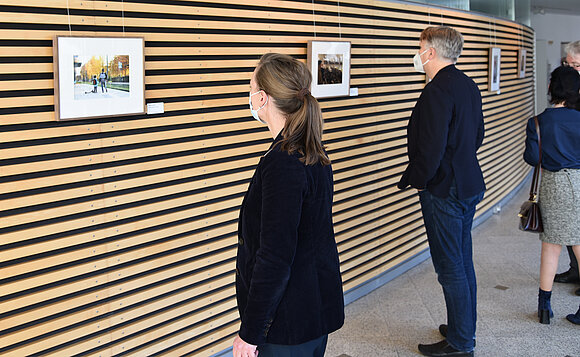Besucher*innen schauen sich die Fotografien ganz genau an.