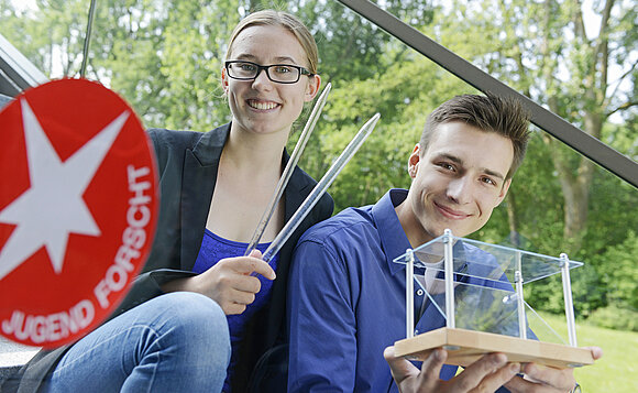 Zwei junge Leute zeigen ihre wissenschaftlichen Untersuchungen.