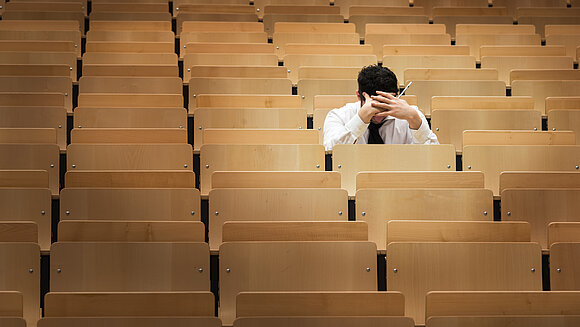 Student sitzt in den leeren Reihen eines Hörsaals.