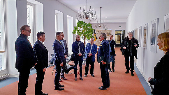 Der Präsident begrüßt Gäste, die ihm locker aufgereiht gegenüberstehen.