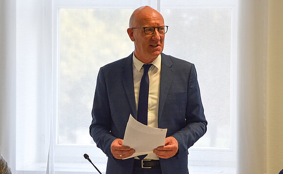 Christian Walbrach, Beauftragter der Landesregierung für die Belange der Menschen mit Behinderungen, spricht stehend zu den Gästen.