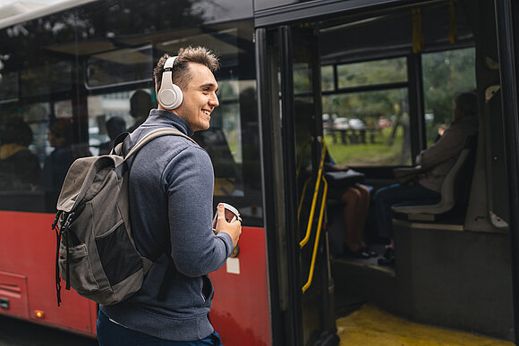 Miljan Živković - stock.adobe.com Ein junger Mann wartet vor einem stehenden Bus auf das Einsteigen.
