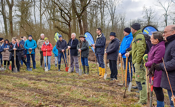 Abgeordnete und Bürger stehen im Halbkreis auf einer Lichtung im Wald.