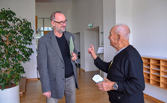 Zwei Männer stehen nebeneinander und unterhalten sich.