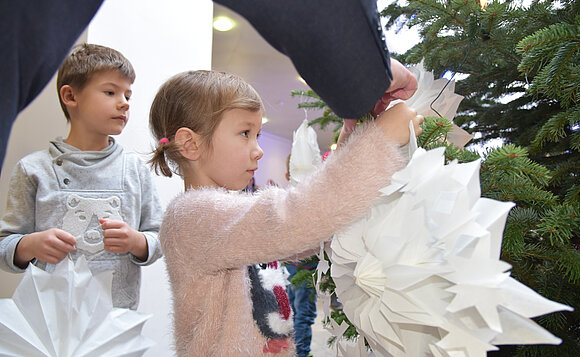 Mädchen und Junge beim Schmücken des Weihnachtsbaums im Foyer des Landtags.