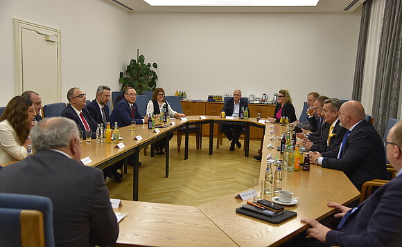 Etwa 15 Personen sitzen für Gesprächsrunde an einem Tisch.