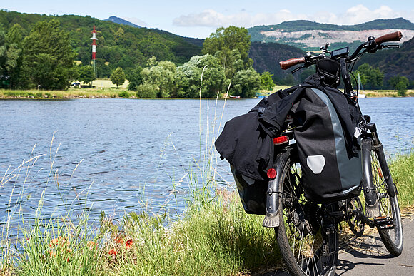 Ein Bild von einem Fahrrad, das auf dem Elberadweg neben dem Fluss abgestellt ist