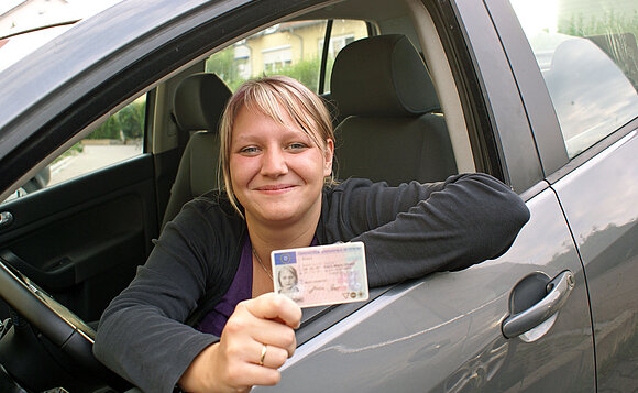 Eine junge Frau hat gerade ihren Führerschein erhalten.