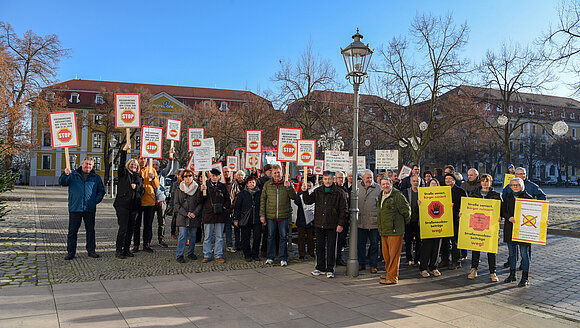 Menschen demonstrieren mit Plakaten vor dem Landtag.