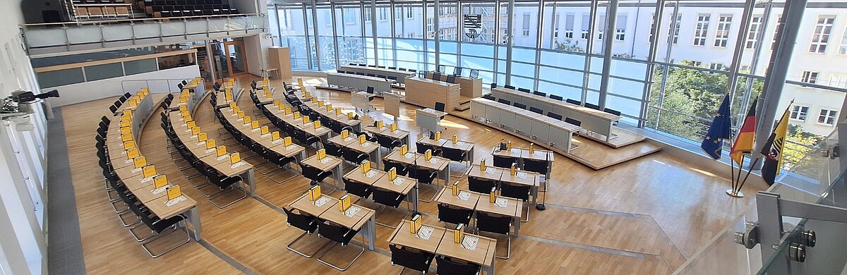 Blick in den leeren Plenarsaal, mit einem Handbuch auf dem Platz eines jeden Abgeordneten.